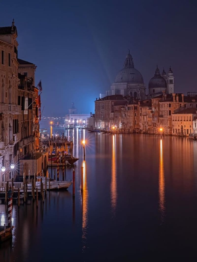 lo stesso tratto di Canal Grande di notte, con le luci dei palazzi riflesse nell'acqua ferma