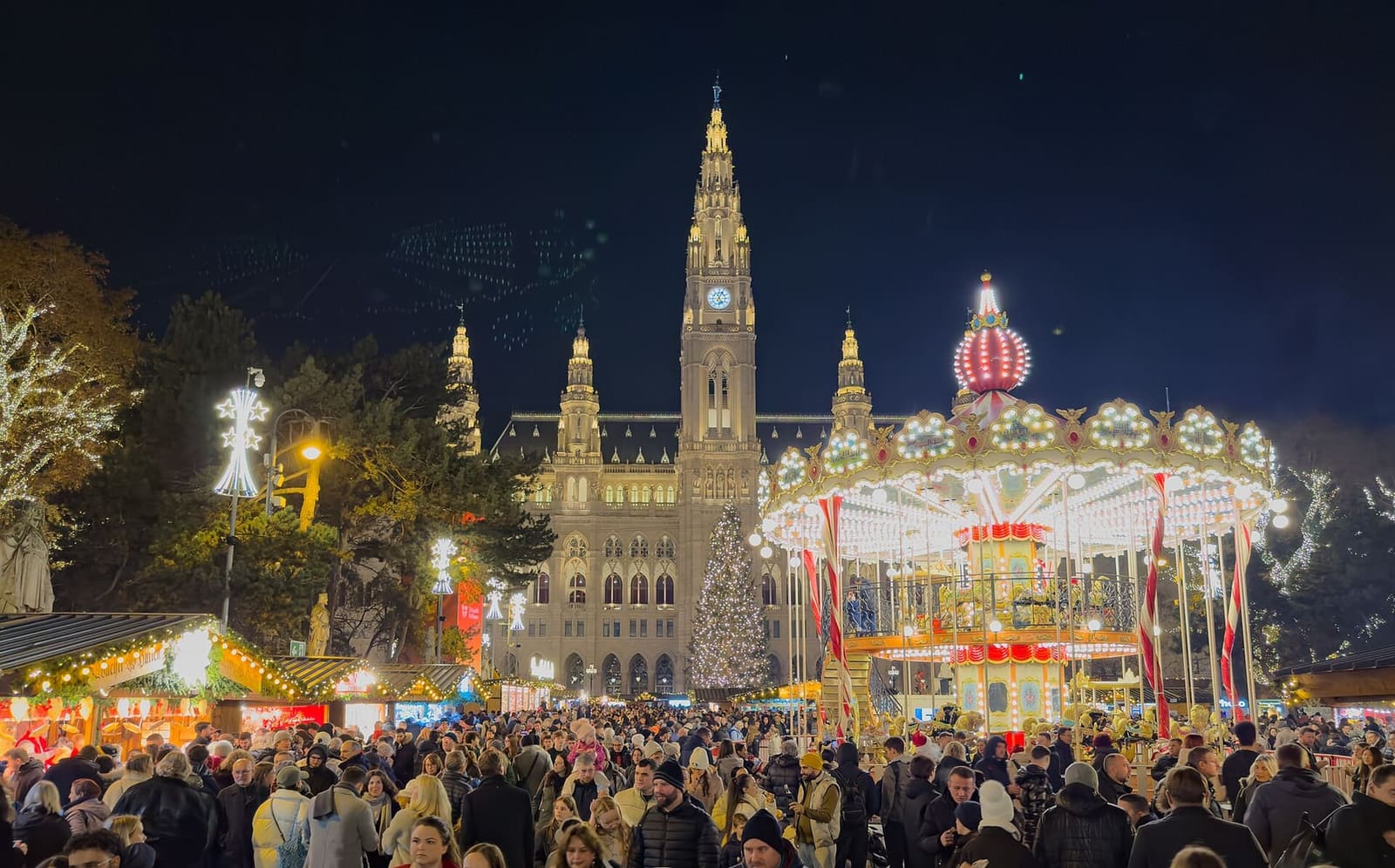 la giostra e la folla del mercatino del Rathausplatz, la sera dell'8 dicembre 2025