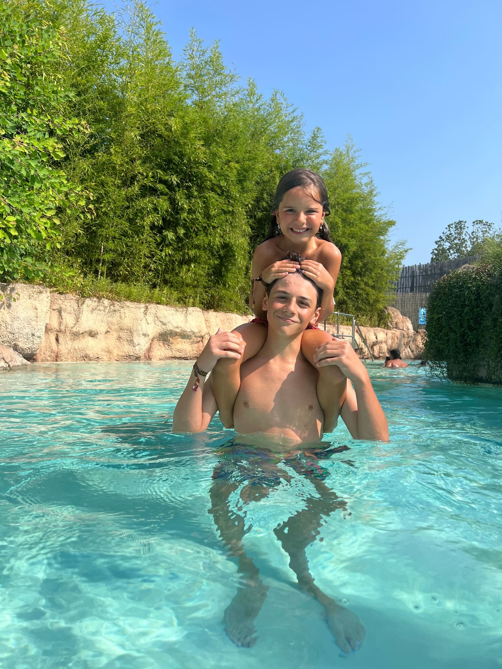 Letizia in piedi sulle spalle di Gabriele, in mezzo alla piscina